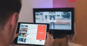 man browsing tablet sitting in front of TV