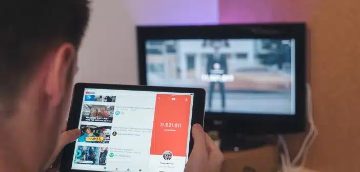 man browsing tablet sitting in front of TV